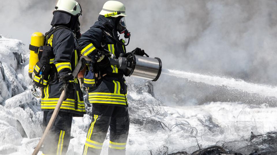 Feuerwehr löscht mit Wasser und Schaum brennende Reifen