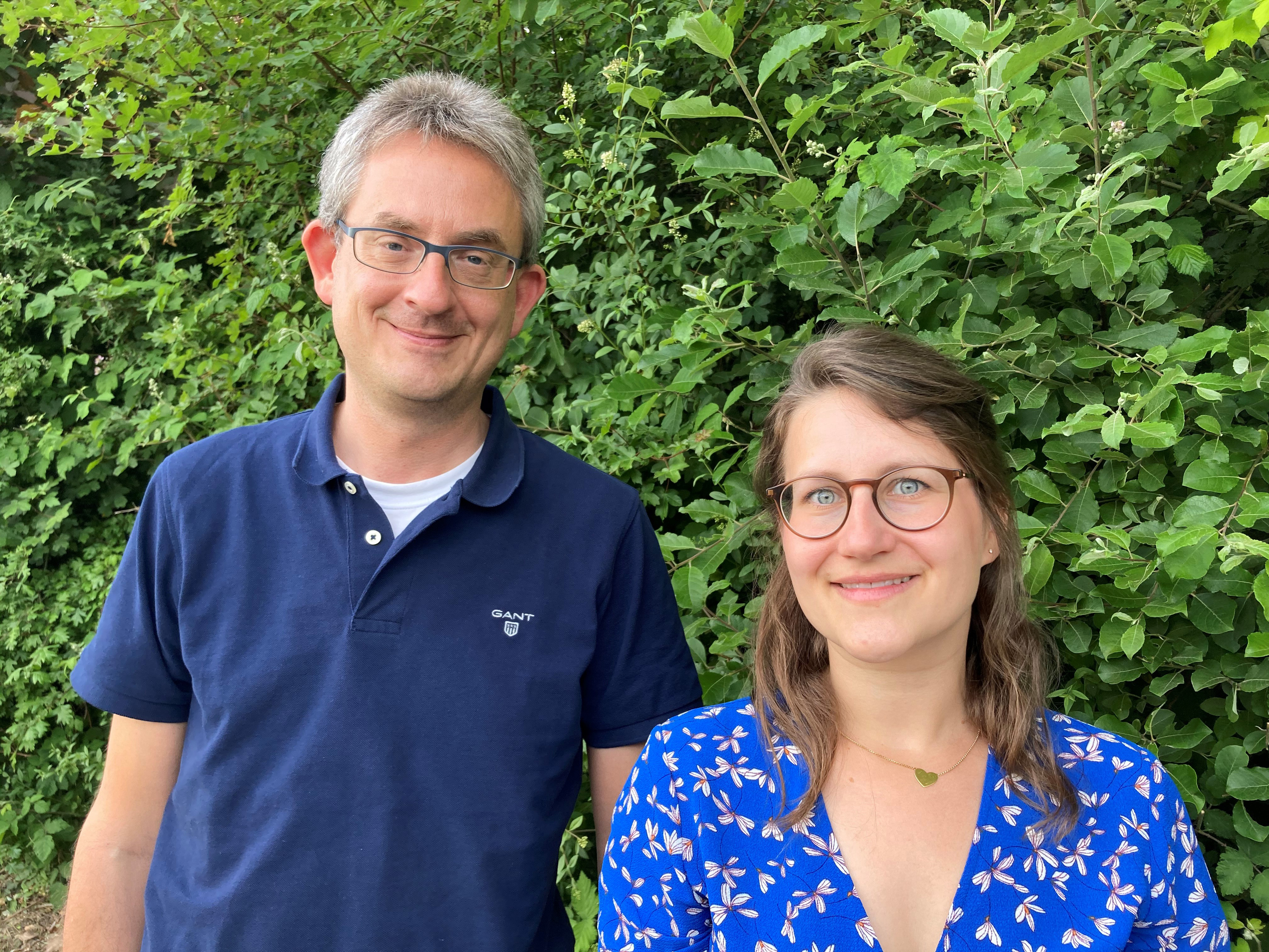 Der Fachberater Herr Siebert und die Fachberaterin Frau Beck vor einer grünen Hecke