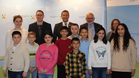 Erklrfilm-Wettbewerb 2023 Sonderpreis Bildung fr Nachhaltige Entwicklung mit mehrsprachlichem Zugang: Klasse 4 a und Lehrkrfte der Grundschule Krefelder Strae in Duisburg mit Regierungsprsident Thomas Schrmann (Mitte hinten), Abteilungsdirektor Thomas Hartmann und Jurymitgliedern /  BR_D