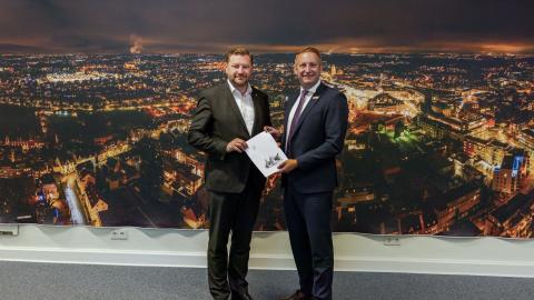 Regierungspräsident Thomas Schürmann (rechts) übergibt den Förderbescheid an Oberbürgermeister Tim Kurzbach.