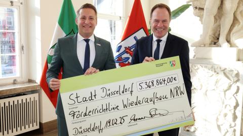 Regierungspräsident Thomas Schürmann (li.) übergibt Förderbescheid an Oberbürgermeister Stephan Keller (re.)