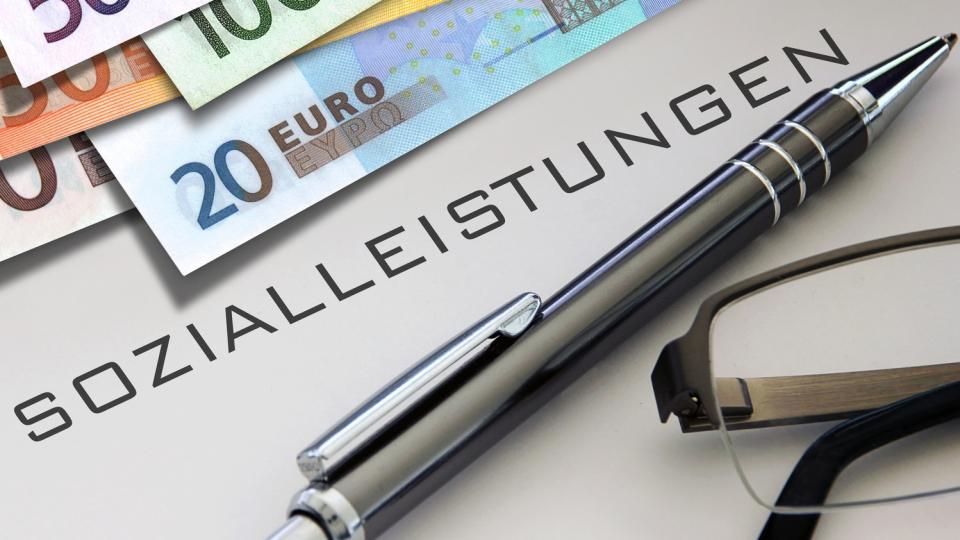 Stift und Geld mit dem Schriftzug "Sozialleistungen" (Symbolbild)