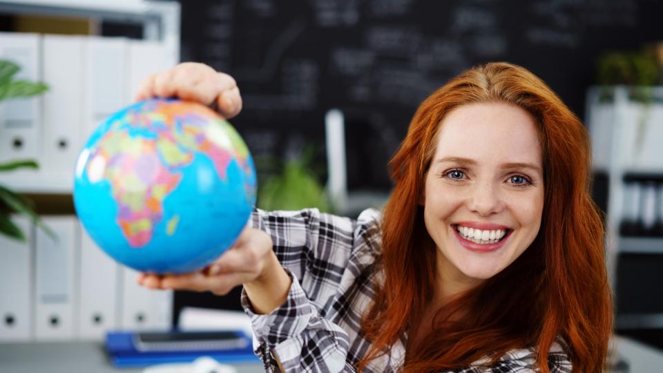 Junge Frau zeigt einen Globus