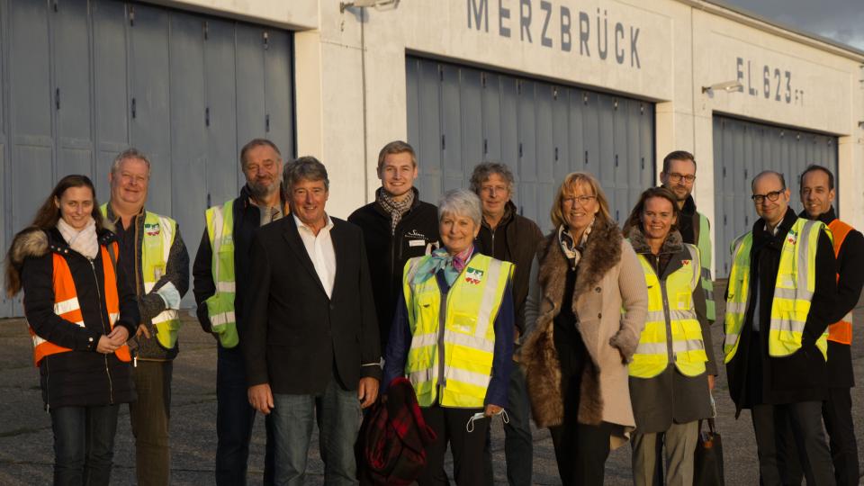 Düsseldorfs Regierungspräsidentin Birgitta Radermacher und die Geschäftsführerin des Flugplatz Aachen-Merzbrück GmbH, Ruth Roelen (M. bzw. 5.v.r.) in großer Runde vor dem Hangar.