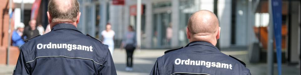 Konzept Ordnung und Sicherheit: Zwei Mitarbeiter des Ordnungsamtes in Uniform auf Streife in der Innenstadt - selektiver Fokus