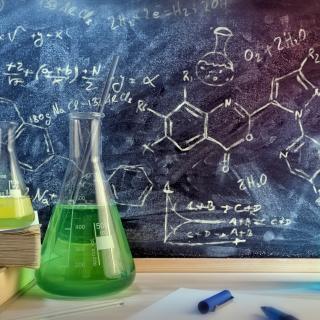 Klassenzimmer Schreibtisch und gezeichnete Tafel des Chemieunterrichts mit Büchern und Instrumenten. Konzept der Ausbildung in den chemischen Wissenschaften. Horizontale Zusammensetzung. Vorderansicht