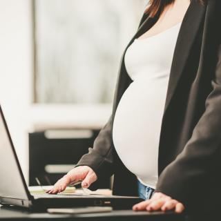 Schwangere Frau, die am Laptop im Büro arbeitet
