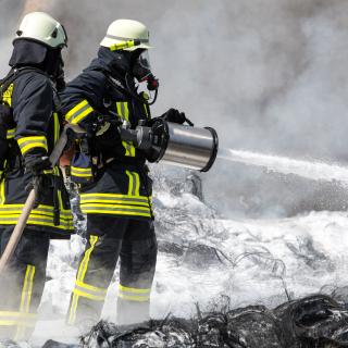 Feuerwehr löscht mit Wasser und Schaum brennende Reifen