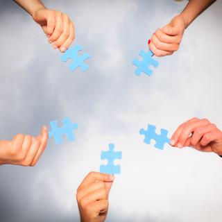 Hände mit Puzzleteilen (Symbolbild)