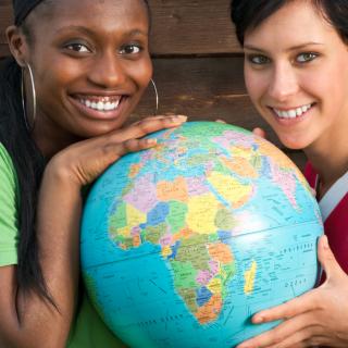 ein afroamerikanisches und ein europäisches Mädchen halten einen Globus