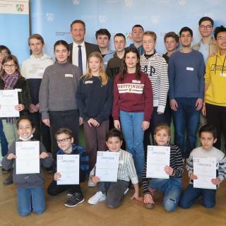 Die Siegerteams des Mathetreff-Online-Teamwettbewerbs 2022 mit Regierungspräsident Thomas Schürmann (Mitte) und Abteilungsleiter Thomas Hartmann (rechts)