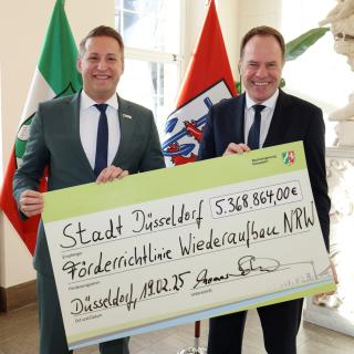 Regierungspräsident Thomas Schürmann (li.) übergibt Förderbescheid an Oberbürgermeister Stephan Keller (re.)